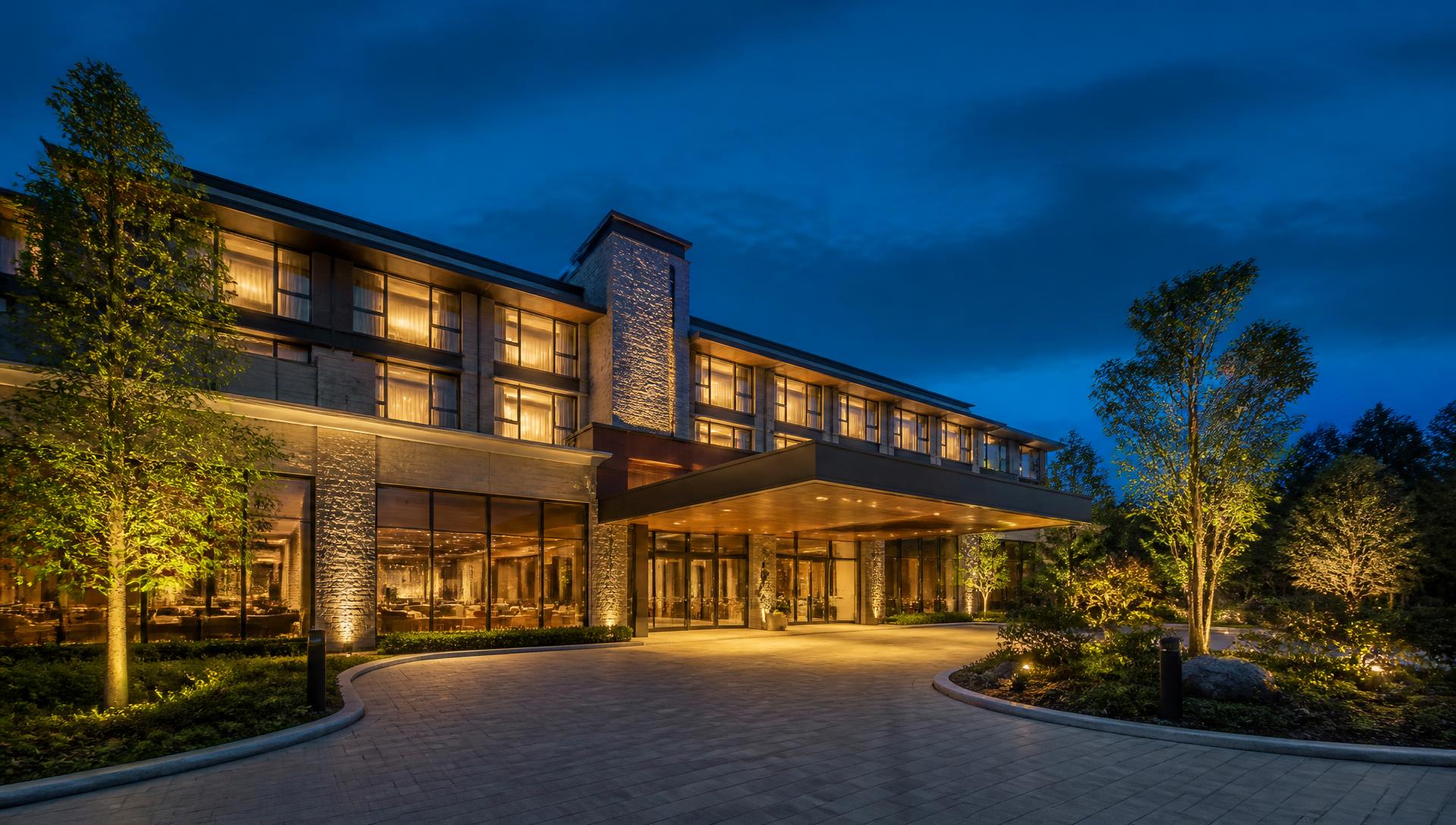 Illuminated hotel entrance at dusk with landscaped driveway